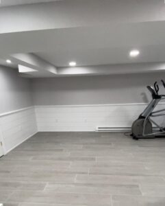 Tile floor installation in a modern home gym with clean gray tiles and seamless alignment.