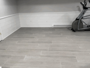 Tile floor installation in a modern home gym with clean gray tiles and seamless alignment.