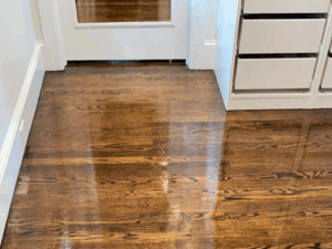 Hardwood refinishing project in Fairfield CT showing glossy restored oak floors next to modern white cabinetry.
