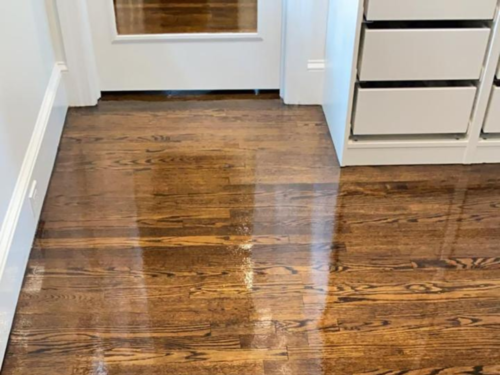 Hardwood refinishing project in Fairfield CT showing glossy restored oak floors next to modern white cabinetry.