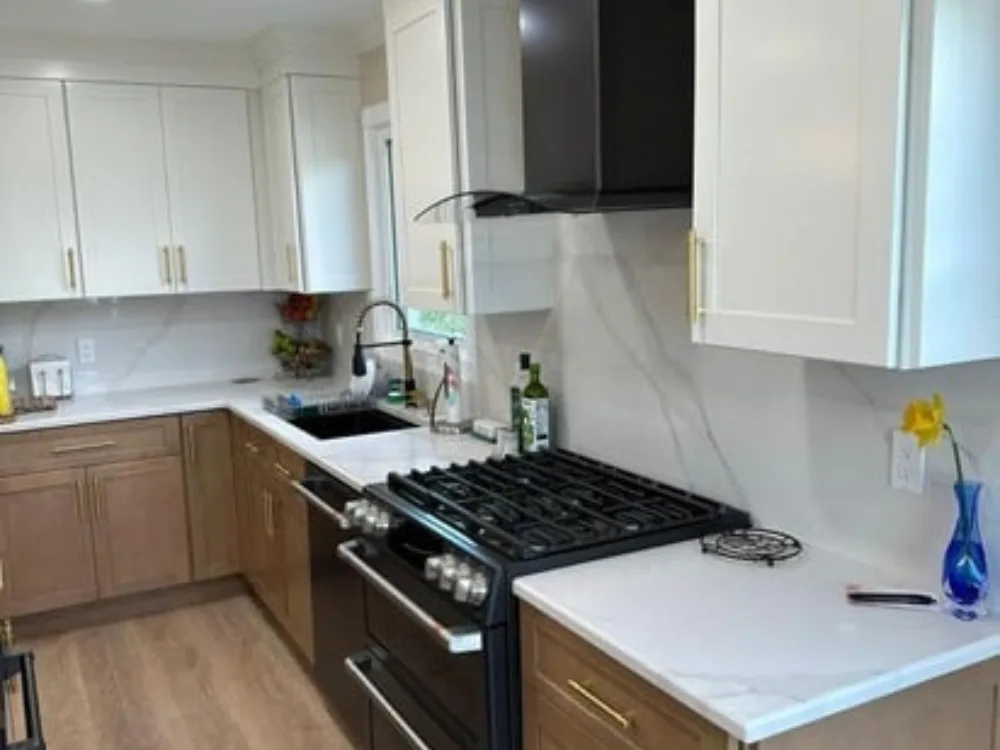 Modern kitchen renovation with two-tone cabinets and quartz countertops.