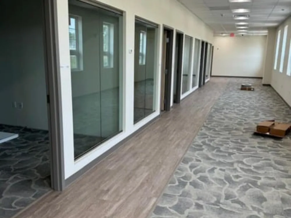 Commercial interior painting, flooring, and door installation in office hallway.