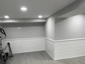 Basement painting project displaying completed basement walls, ceiling lighting, and floor finish
